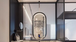 Un baño moderno con un espejo independiente, un lavabo con encimera moteada y dos toallas colgadas en un perchero.