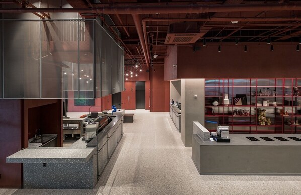 Un interior moderno con una zona de cocina, una sala de estar y una exhibición de objetos en estanterías.