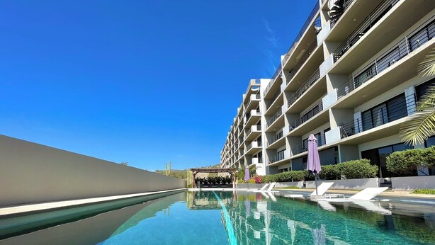 A modern hotel with a clear swimming pool, multiple balconies, and lush landscaping. - Marea Sabina Luxury Ocean View & Amenities (Cabo San Lucas)