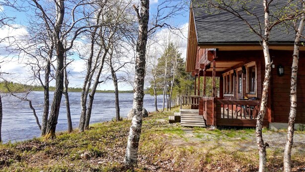 Une cabane en bois avec une véranda donnant sur un lac.