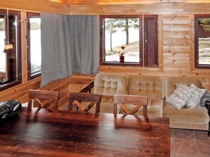 L’intérieur d’un chalet en bois comprend une table à manger, des chaises, un canapé et de grandes fenêtres.