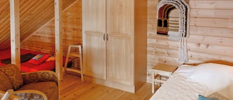 Un interno in legno con un letto, una sedia, un armadio e un piccolo tavolo.