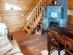 Un intérieur en bois avec une cheminée, un escalier et un coin repas.
