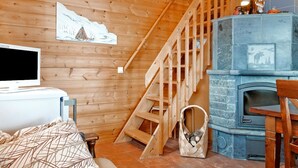 Un intérieur en bois avec une cheminée, un téléviseur et un canapé.