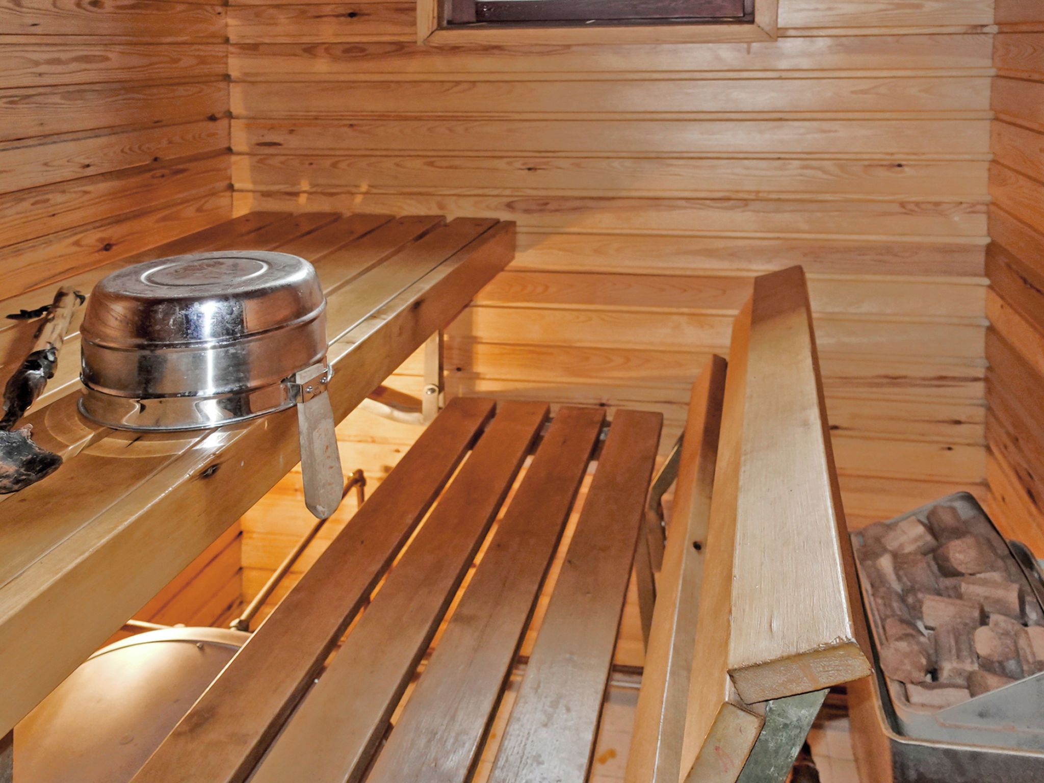 A sauna room with wooden benches and a metal sauna heater.