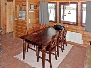 Une table de salle à manger en bois, avec des chaises, un coin cuisine et une vue sur l’extérieur.