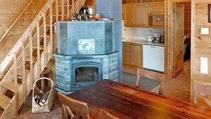 Un intérieur en bois avec une cheminée en pierre, un escalier en bois et un coin cuisine.