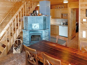 Un intérieur en bois avec une cheminée en pierre, un escalier en bois et un coin cuisine.