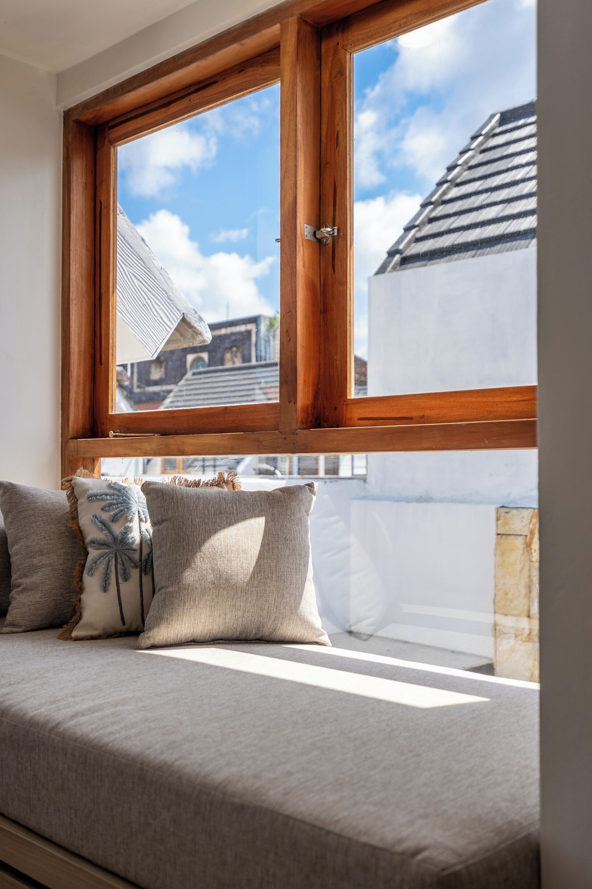 Una cama con vista a un edificio a través de una ventana con marco de madera.