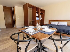 A dining area with a wooden table set for four, surrounded by four chairs with woven seats. - Peregrina Tulum 110 1BR Lux with Jacuzzi (Tulum)