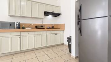 A kitchen with white cabinets, a stainless steel refrigerator, a microwave, and a sink.