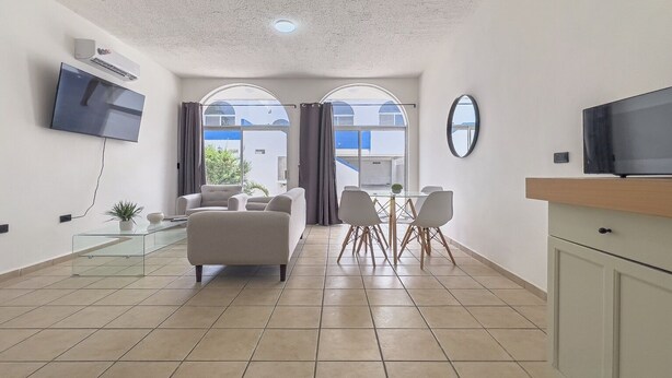 A modern living room with a sofa, TV, and dining area. - Balandra Housing 2BR home downtown LPZ walk everywhere (La Paz)