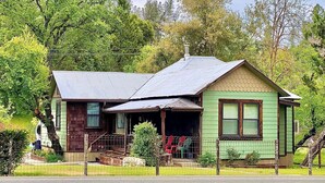 A two-story house with a green exterior and a metal roof.