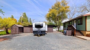 A recreational vehicle (RV) named 'MINILITE' parked in a gravel driveway with a small wooden shed and a house in the background.