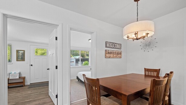 A dining area with a wooden table and chairs, a chandelier, and a welcome sign.