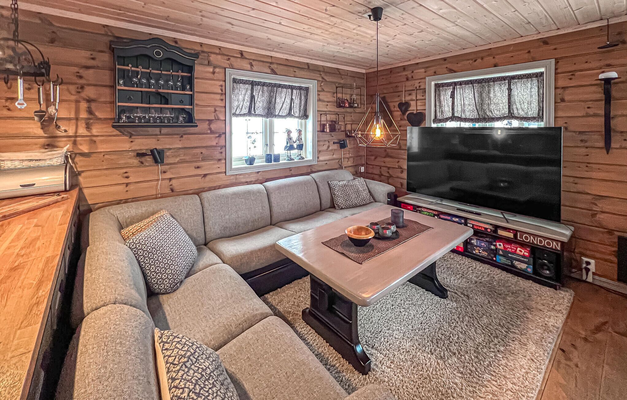 Ein gemütliches Wohnzimmer mit einem Ecksofa, einem Holz-TV-Schrank und einem Kamin.