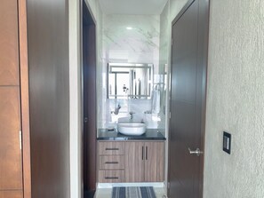 Un baño moderno con tocador de mármol, lavamanos y espejo.