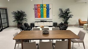 A modern dining area with a wooden table, white chairs, a colorful abstract painting, and potted plants. - New Studio Downtown Miami Bay View Rooftop Pool. (Miami)