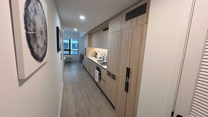 A narrow hallway with a kitchen area featuring wooden cabinets and a countertop with kitchen appliances. - New Studio Downtown Miami Bay View Rooftop Pool. (Miami)