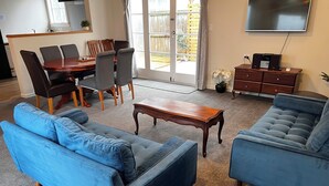 Un salon avec deux canapés bleus, une table basse en bois et un coin repas comprenant une table et des chaises.