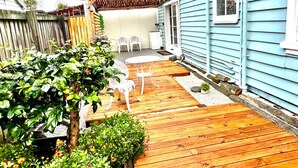 Une terrasse en bois avec une table et des chaises, entourée de plantes en pot et d’une clôture en bois.