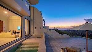 A modern outdoor living area with a pool, a sofa, and a dining table. - Villa Vista al Mar (Uluwatu)