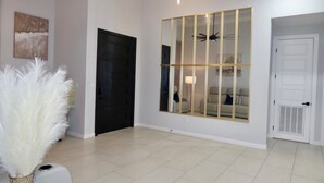 A modern interior with a large mirror, a black door, and a white door. - 3-bedroom house (Alton)