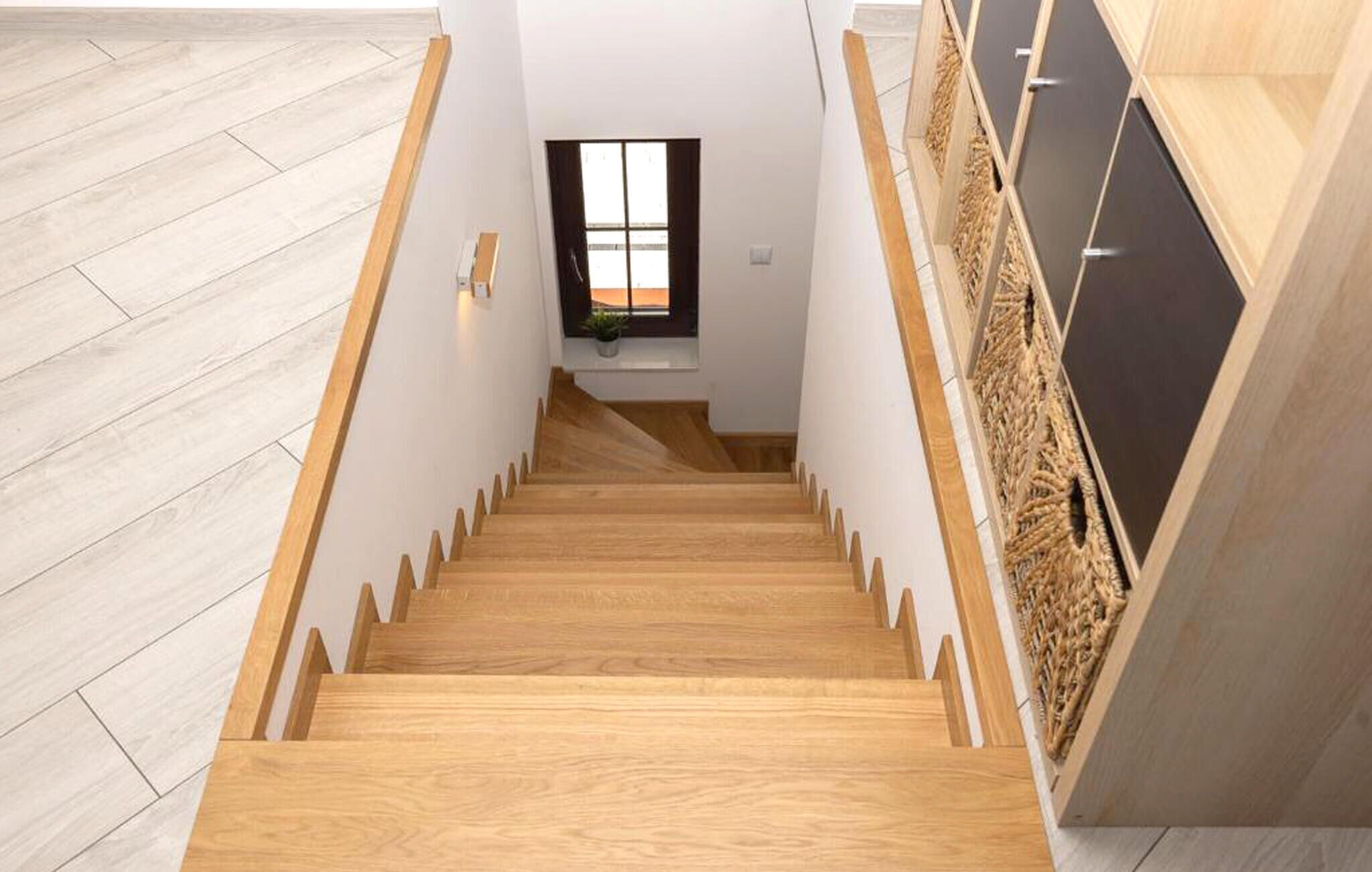 Un escalier en bois donnant sur une fenêtre et une plante.