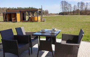 A small wooden cabin with a porch, a table with chairs, and a field in the background. - Beautiful home in Koden with sauna (Koden)
