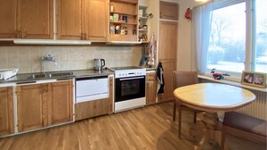 A kitchen with wooden cabinets, a dishwasher, an oven, a sink, and a dining table with chairs. - 3 bedroom beautiful home in Borgholm (Borgholm)