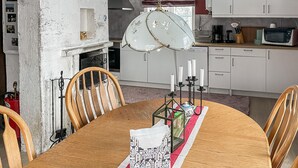A dining area with a wooden table, chairs, a chandelier, and a kitchen in the background. - 1 bedroom lovely home in Söderköping (Söderköping)