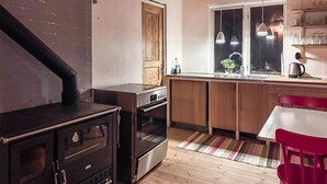 A compact kitchen with a wood stove, a sink, and a window overlooking the street.