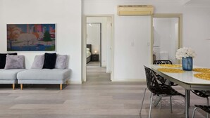 Un salon moderne avec un canapé, une table à manger et des chaises, ainsi qu’un tableau accroché au mur.