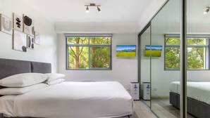 Une chambre moderne avec un grand lit, une table de chevet, une armoire et une cloison en verre.