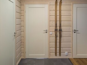 Un pasillo con tres puertas, una de ellas con esquíes colgados en la pared.