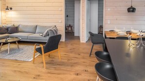 Acogedor interior de cabaña con sala de estar, comedor y una escalera que lleva a un nivel superior.