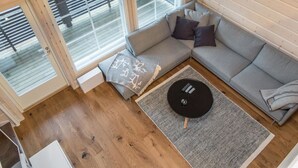 Una sala de estar moderna con un sofá seccional gris, una mesa de centro redonda negra y una alfombra estampada.