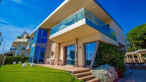 Une maison moderne à deux étages, dotée d’un toit plat, de grandes fenêtres et d’une pelouse bien entretenue.