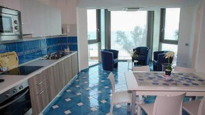 Une cuisine moderne aux carreaux bleus et blancs, un coin repas avec une table et des chaises, et de grandes fenêtres offrant une vue dégagée.