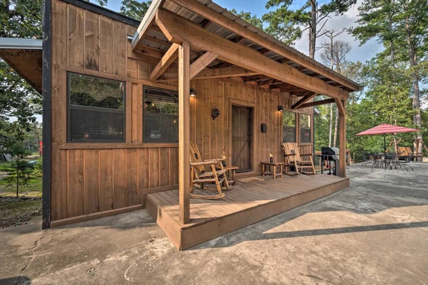 A wooden cabin with a porch, outdoor seating, and a grill area.