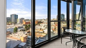 Een hoog gelegen kamer met grote ramen en uitzicht over de stad.