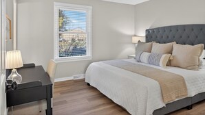 Un dormitorio con cama, escritorio, silla, ventana y ventilador de techo.