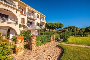 A multi-story building with balconies, stone pathway, and well-maintained lawn. - Il Vecchio Faro Carolina, Porto San Paolo, Italy (Porto San Paolo)