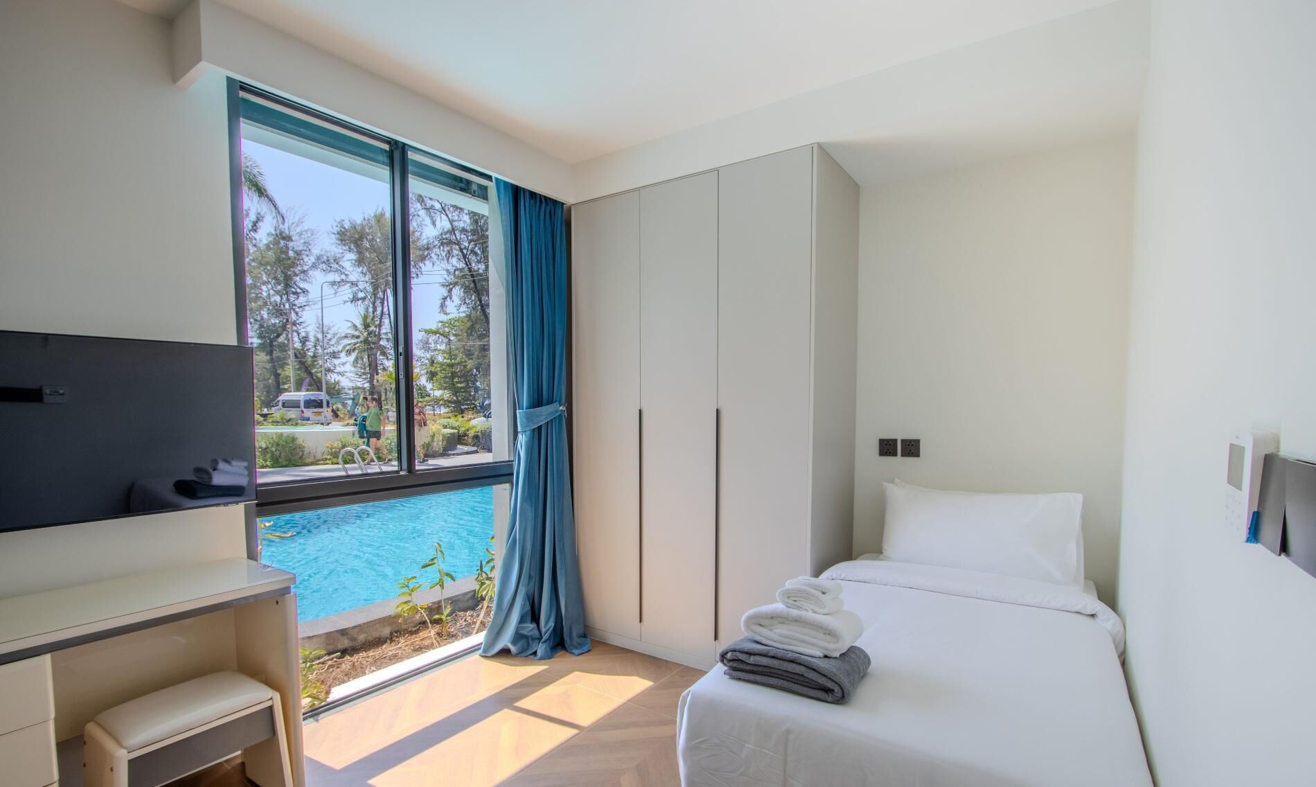 Une chambre d’hôtel avec un lit, un bureau, une télévision et une fenêtre donnant sur une piscine.