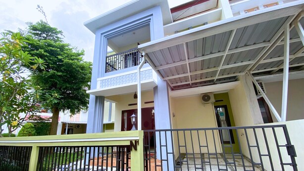 A two-story building with a balcony on the upper floor, a gated entrance, and a staircase leading to the entrance. - Home Sweet Home Dekat UMY by Simply Homy (Sleman)
