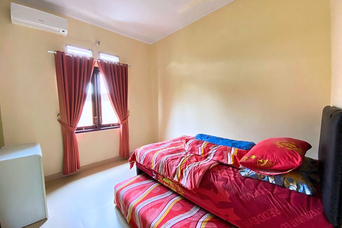 Un dormitorio con cama, cortinas, unidad de aire acondicionado y ventana.