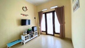 A room with a television, a bench, a cabinet with electronic devices, and a door with curtains. - Home Sweet Home Dekat UMY by Simply Homy (Sleman)