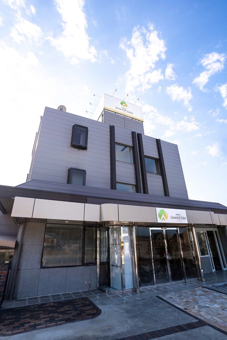 Un moderno edificio de hotel con techo plano, amplia entrada de vidrio y un letrero que indica que es el Greenhill Golf Hotel.