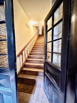 A staircase leading to a second floor with a dark wooden door and a window with a view of the outside. - Old Town T8 SELF Check In (Vilnius)