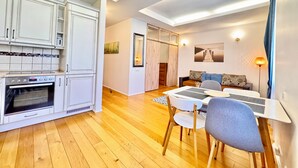 Una cuina moderna amb armaris blancs, forn integrat i zona de menjador amb taula i cadires.